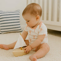 Baby im coral-pinken Fresk Kurzarmbody mit Hummer-Print sitzt im Babyzimmer und spielt – weicher Bio-Baumwollbody, alltagstauglich und schönes Geschenk zur Geburt.