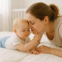 Baby kuschelt mit Mama auf hellem Bett und trägt eine hellblaue Fresk Babyhose – atmungsaktive Bio-Baumwolle, Größe 62–68; bequem für Alltag und Spielzeit.