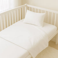 Weißes Julius Zöllner Bettwäsche-Set (80×80/35×40) sauber bezogen im Babybett – 100 % Baumwolle, OEKO-TEX Klasse 1.