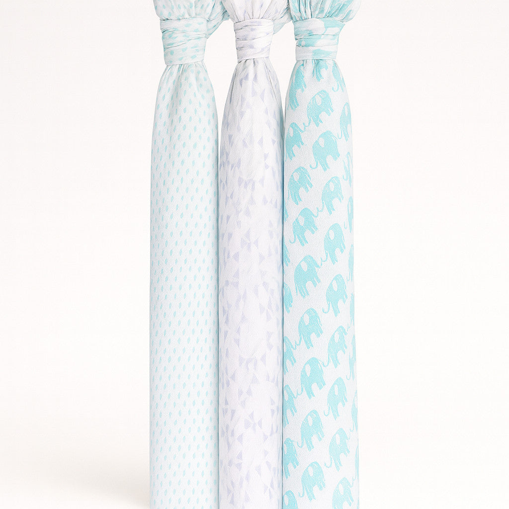 Drei Musselin Swaddle-Tücher von Julius Zöllner, 120×120 cm, weiß/mint mit Punkt-, Dreieck- und Elefanten-Print, nebeneinander aufgehängt.