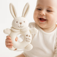 Baby hält den weißen Maximo Greifring Hase – weiches Greifspielzeug für erste Motorik, ideal für Erstausstattung und Babygeschenk.