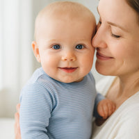 Baby auf dem Arm trägt blau gestreiftes Pippi Baby T-Shirt (60 cm) – sanfte Baumwolle, alltagstaugliches Oberteil für die Baby Box.