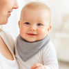 Baby auf dem Arm trägt hellgraues Pippi Halstuch – weiches Dreieckstuch mit Druckknöpfen, hält trocken beim Zahnen; praktische Ergänzung fürs Newborn-Set und schönes Geburtsgeschenk.