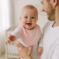 Papa hält lachendes Baby mit rosa Pippi Halstuch – saugfähiges Sabbertuch in Einheitsgröße, pflegeleichtes Lätzchen, liebevolles Geburtsgeschenk.