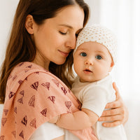 Mama hält Baby mit Pippi Mullwindel lotus mit Heißluftballon-Print über der Schulter – saugfähiges Spucktuch 70×70 cm aus Baumwolle, praktisch für Wickeltasche und Baby Box.