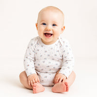 Weißer Sanetta Langarmbody mit dezentem Print am sitzenden Baby im Studio; weiches Feinripp aus Bio-Baumwolle, bequemer Sitz, GOTS-zertifiziert und pflegeleicht – ideal für die Baby-Erstausstattung.