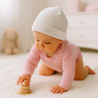 Rosa-weiß geringelter Sanetta Langarm-Babybody aus GOTS-zertifizierter Bio-Baumwolle beim Krabbeln im Babyzimmer – weich, atmungsaktiv und ohne Seitennaht; ideales Basic für die Erstausstattung und den Alltag.