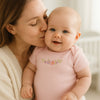 Rosa Schnizler Kurzarm-Babybody mit Pünktchen und Blumenprint am Baby, Mama gibt einen Kuss – hautfreundliche Baumwolle, pflegeleicht und komfortabel; ideal für die Erstausstattung in Größe 50–56 cm.