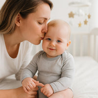 Baby im grau-weiß gestreiften Bio-Body von Sense Organics (50–56 cm) – weiches Alltagsstück, passt perfekt in die Baby Box oder als kleines Geburtsgeschenk.