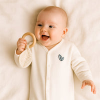 Baby trägt naturweißen Sense Organics Schlafanzug mit Füßchen und Druckknöpfen, GOTS-zertifizierte Bio-Baumwolle – gemütliche Babykleidung.